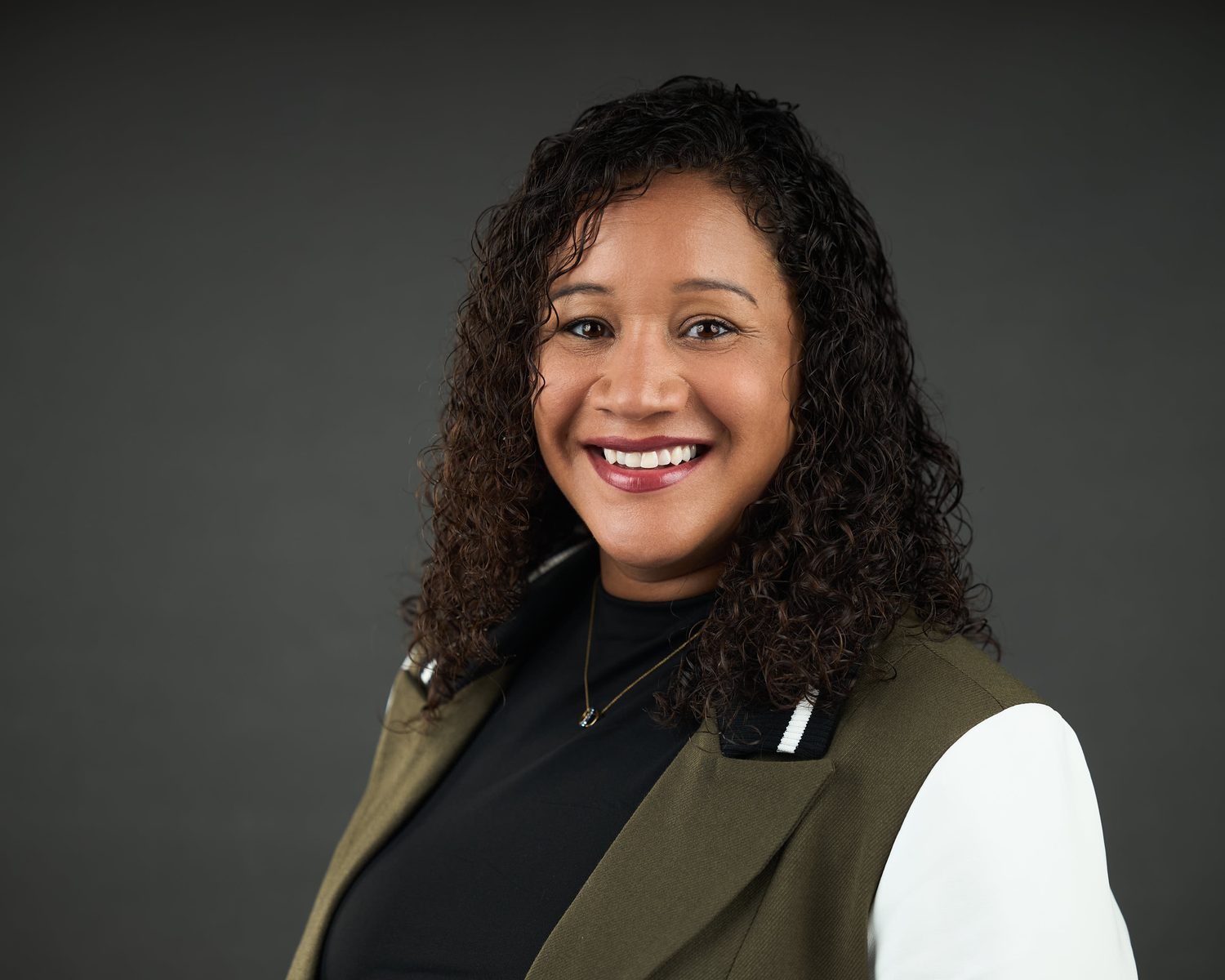 Headshot of a woman in a green jacket over a patterned top