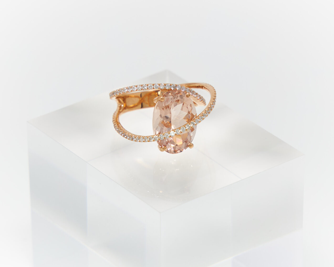 Morganite and diamond rose gold ring on a clear acrylic block